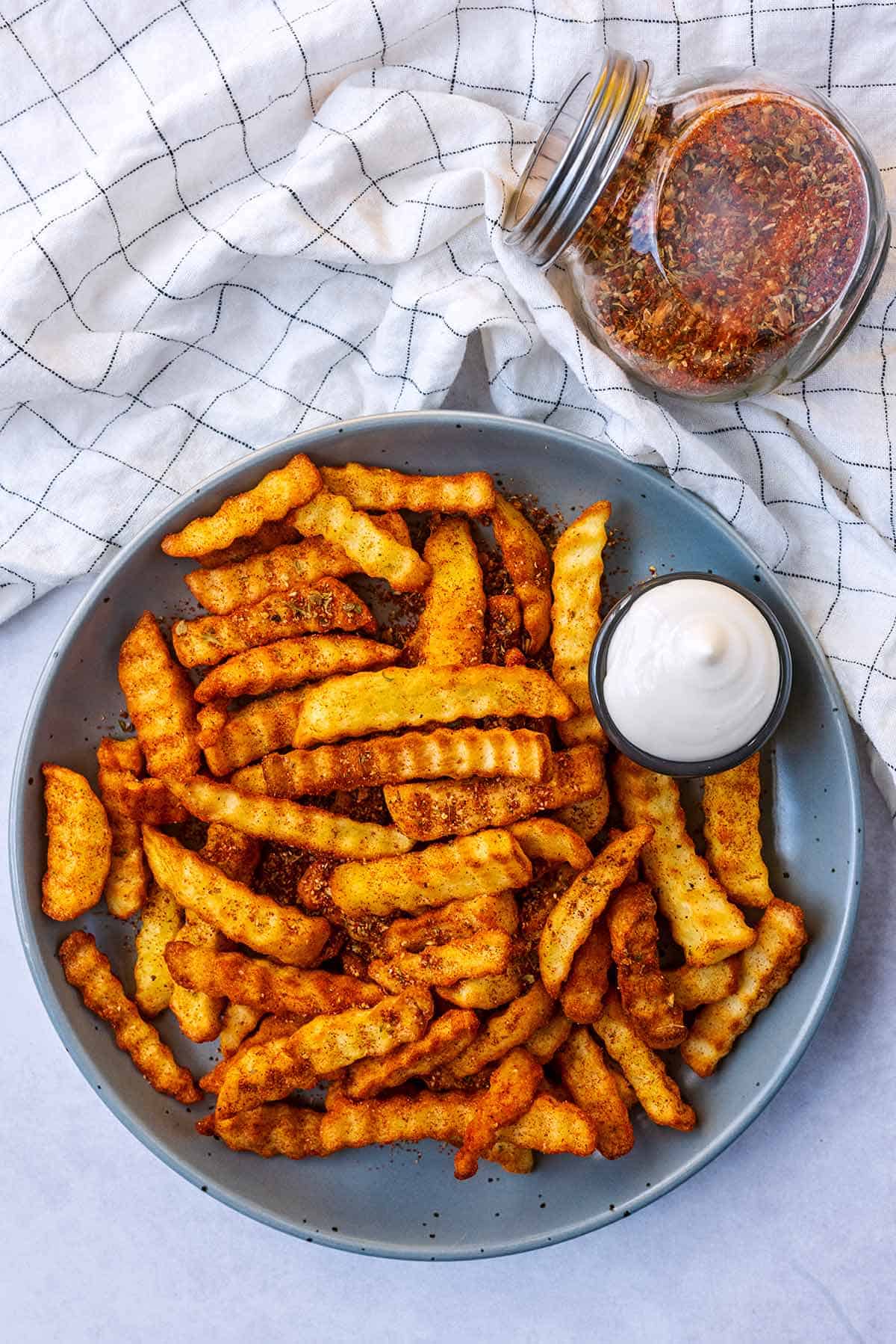 Plate of peri peri fries and a side of dipping sauce on the plate. 