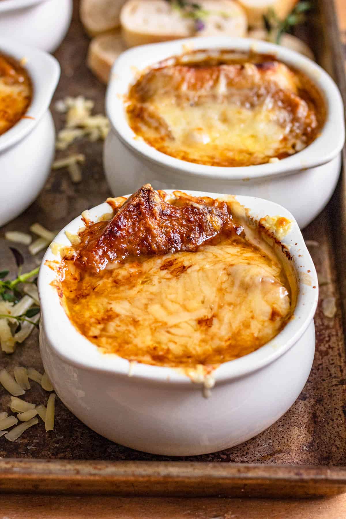 Soup crocks of French onion soup with melted cheese over bread soaked in rich beef broth. 