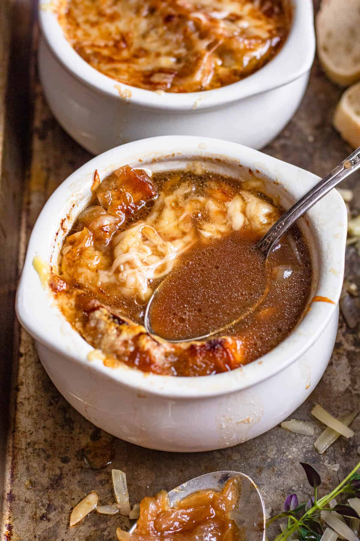 Spoonful of french onion soup being lifted out of a bowl of melted cheese.