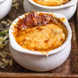 A large crock of French Onion Soup with melted cheese on top.