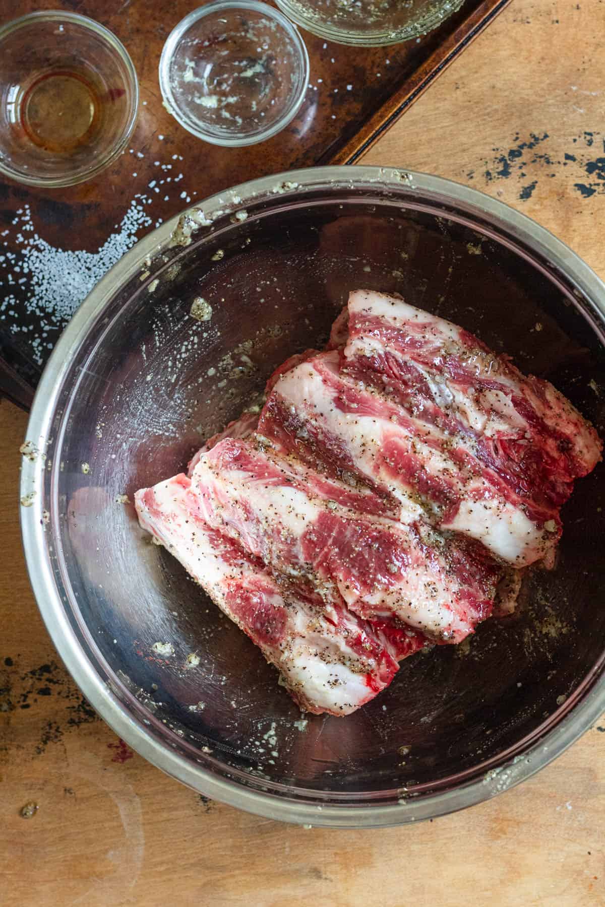 Marinade covering the goat ribs in a mixing bowl. 