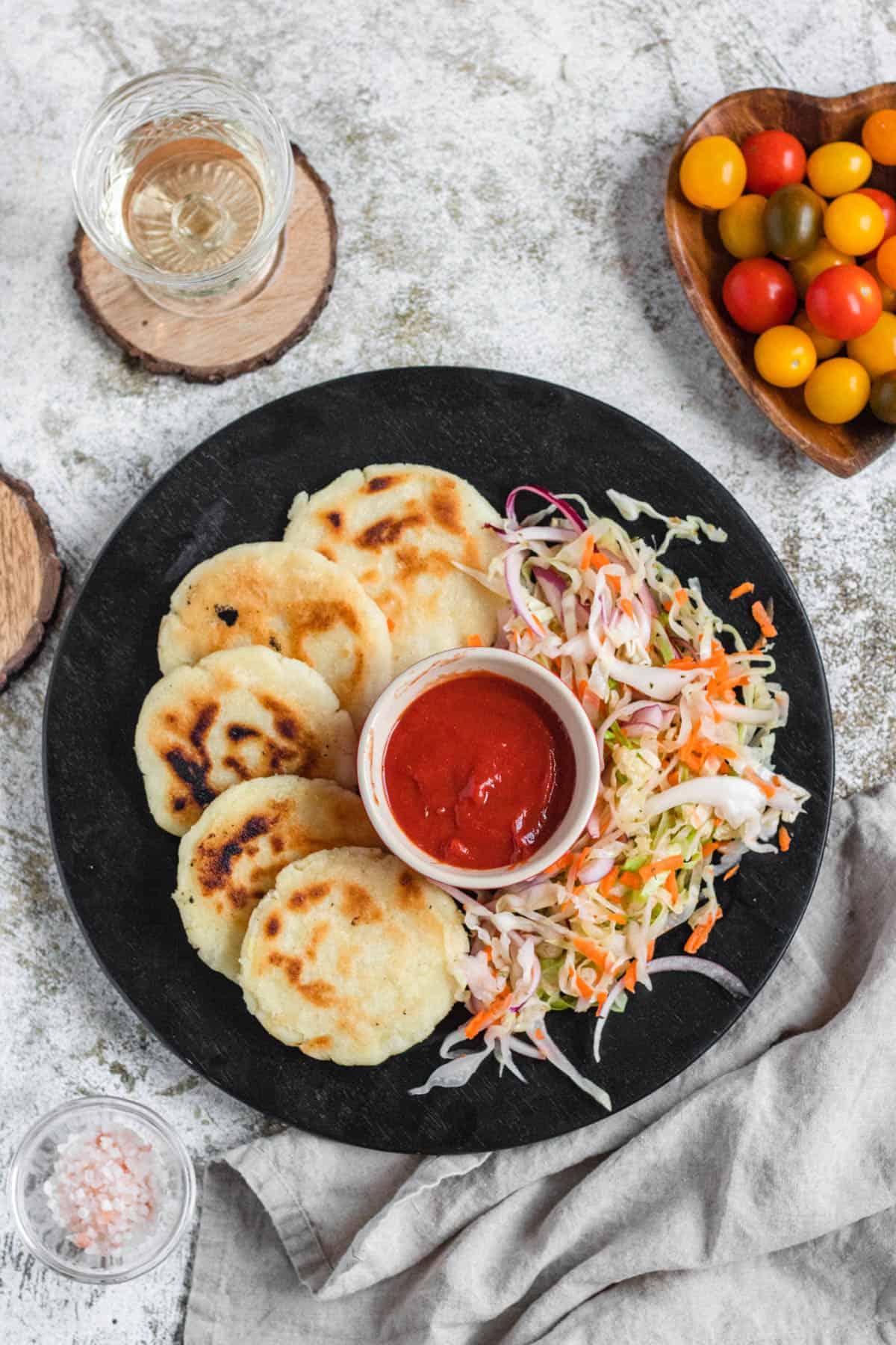 Pupusas served on a plate with curtido on the side and a side of dipping sauce in the middle. 