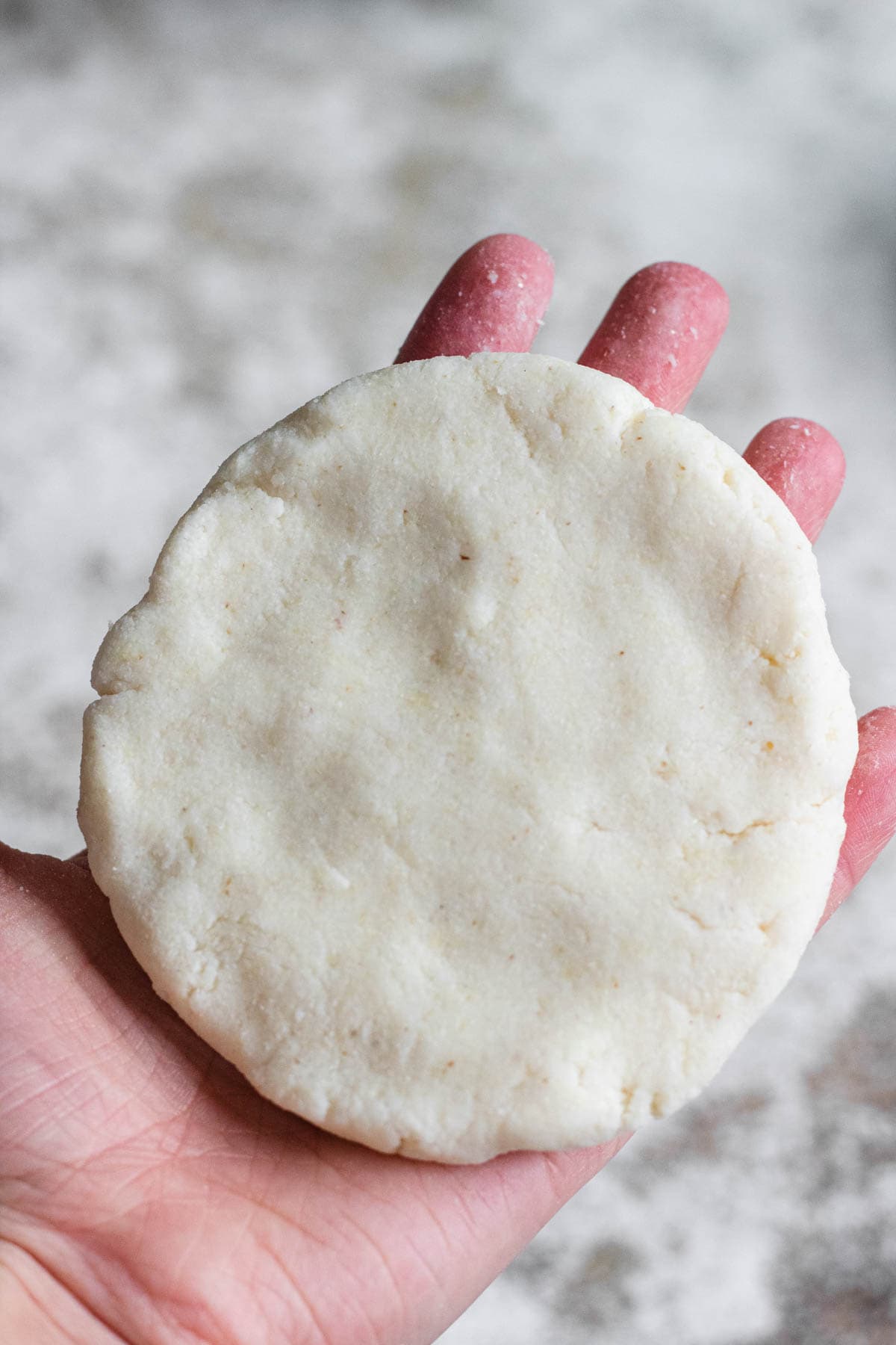 The cheese covered by the pupusas dough to make a flat pupusa, ready to add to the griddle. 