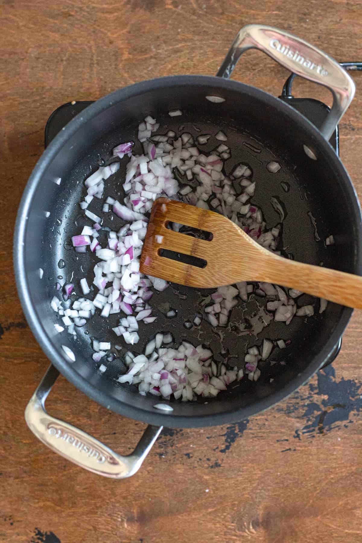 Diced red onion sauteing in a saucepan. 