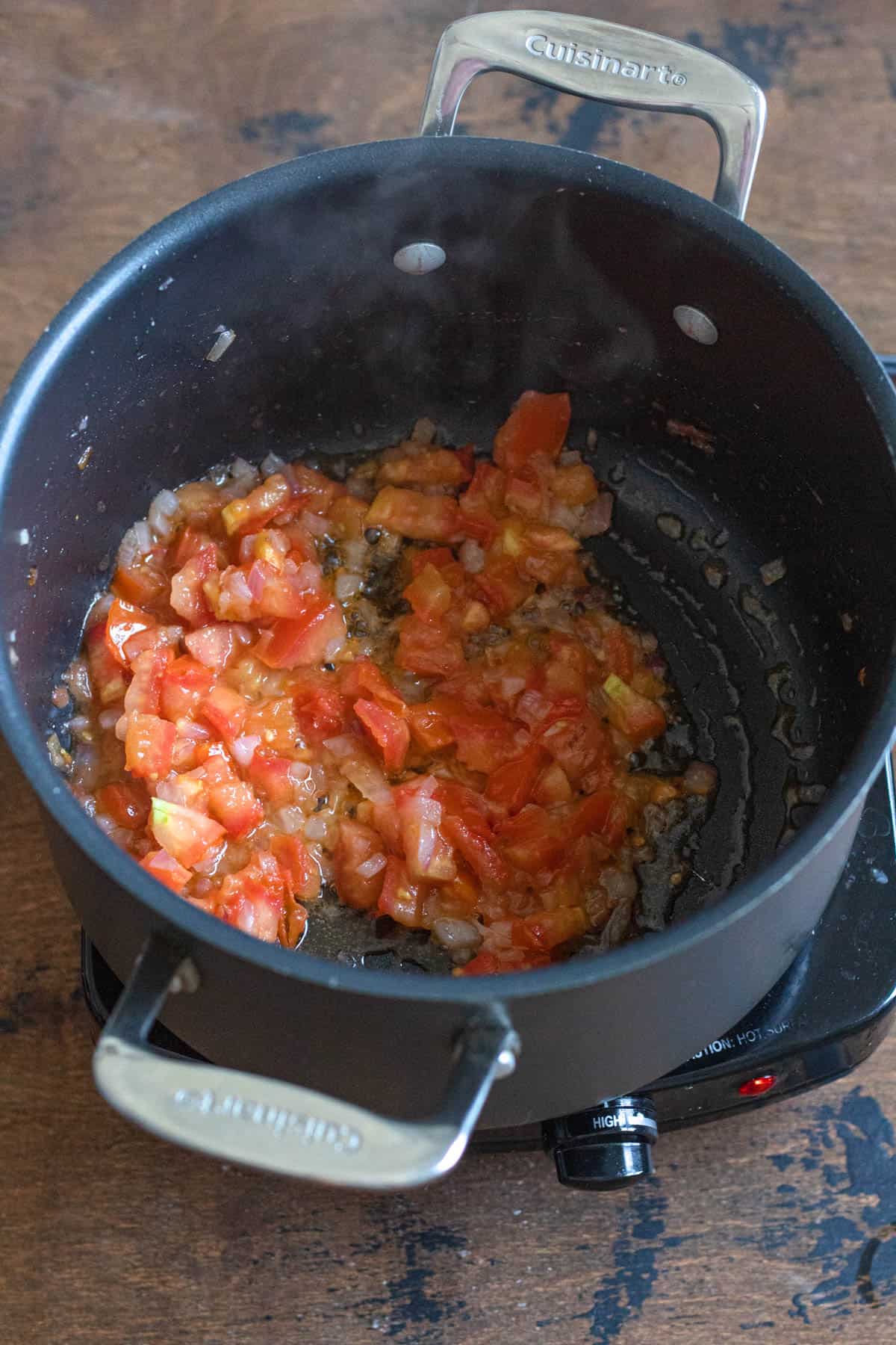 Roma tomatoes added to the red onions in a saucepan. 