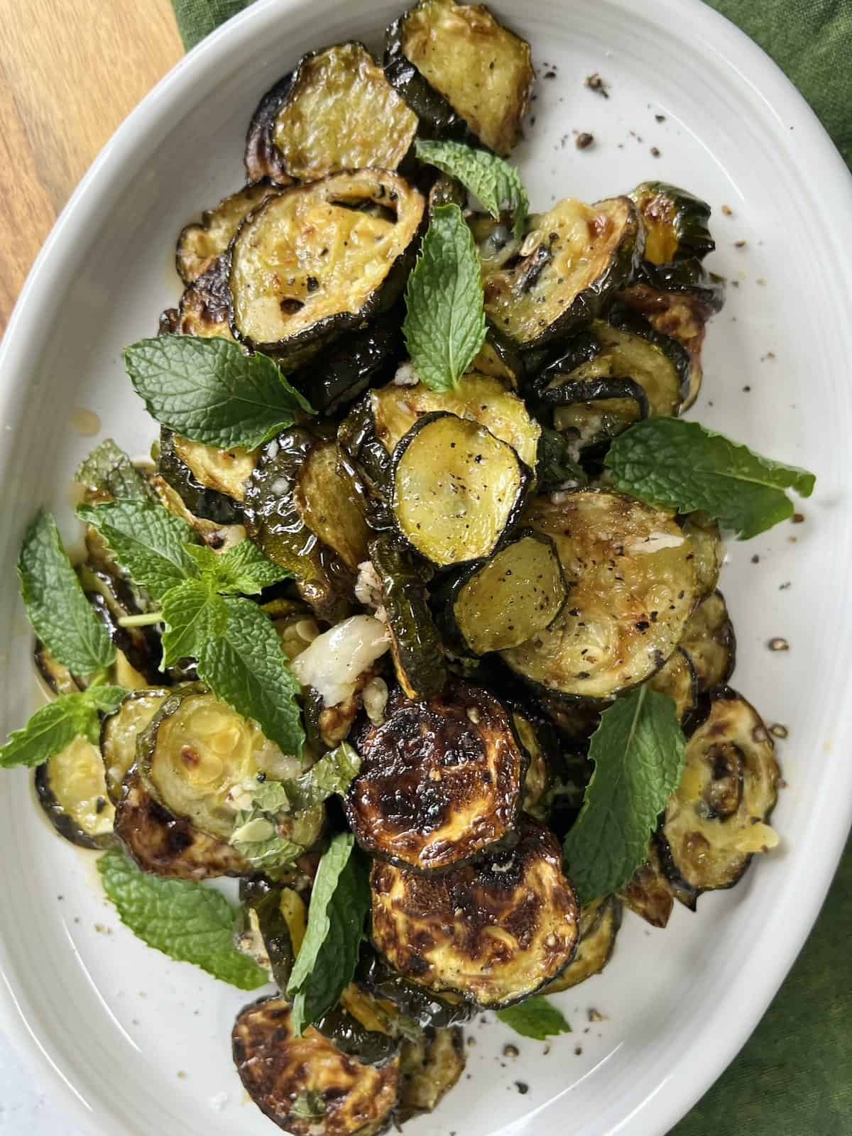 Roasted zucchini alla scapece served on a platter with fresh mint sprigs. 