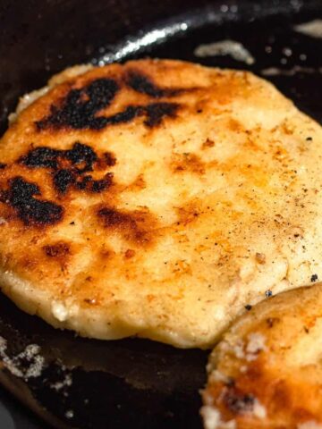 Cheese stuffed golden arepas on a griddle, ready to serve.