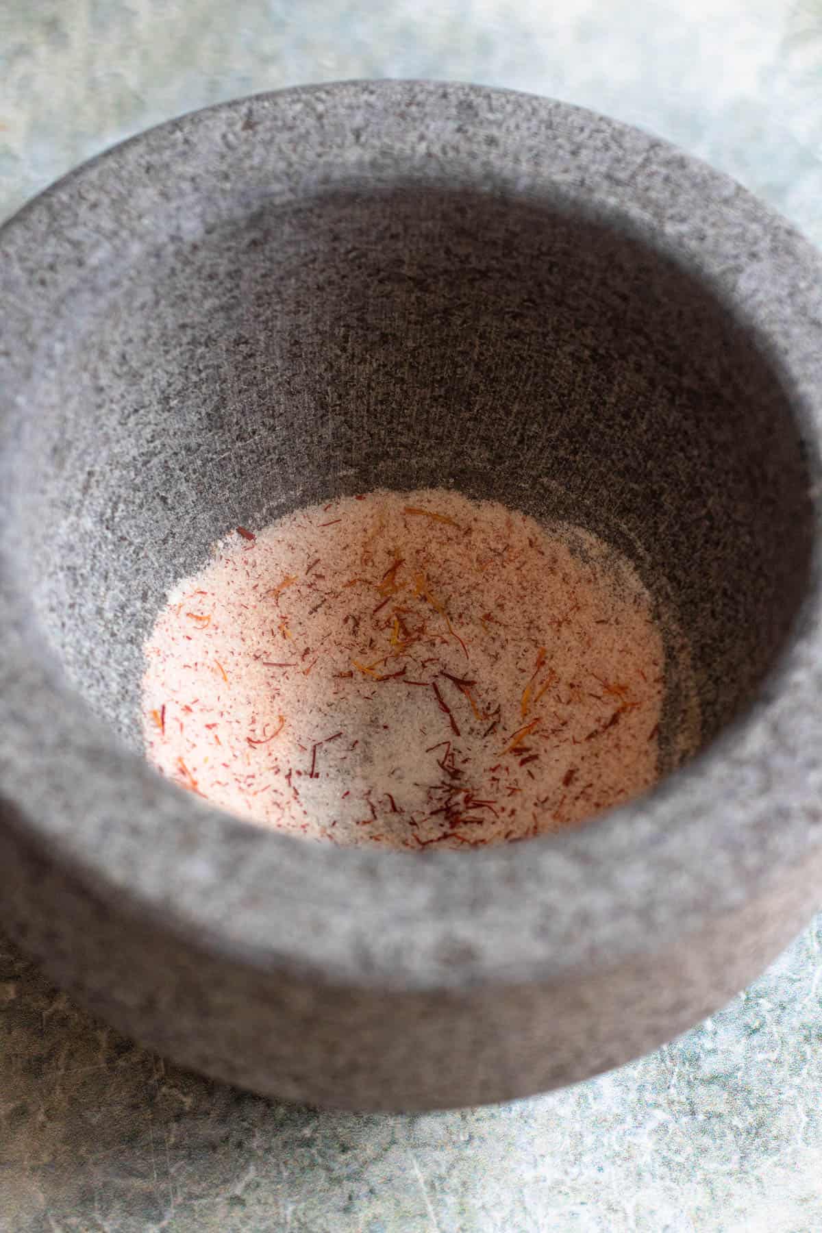 Sugar and saffron added to a mortar to grind down the saffron in prep for a cardamom cake. 