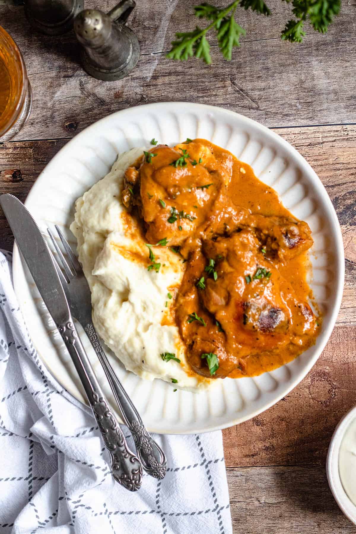 Chicken paprikash recipe served over a bed of mashed potatoes and garnished with parsley. 