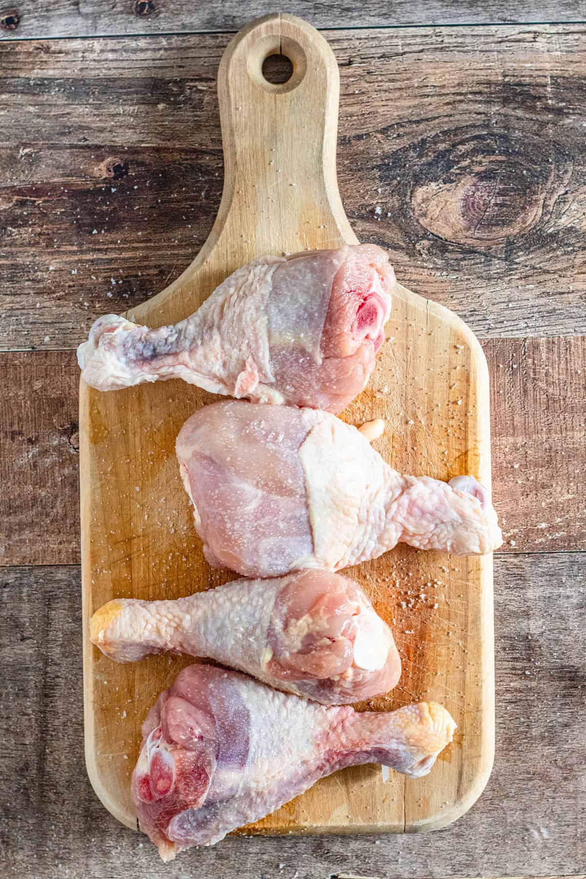 Salted raw chicken on a wooden cutting board to prepare Chicken paprikash recipe. 