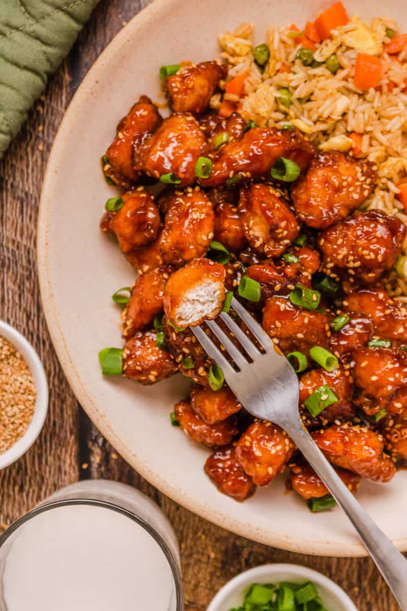 Baked honey sesame chicken with fried rice served on a plate. 
