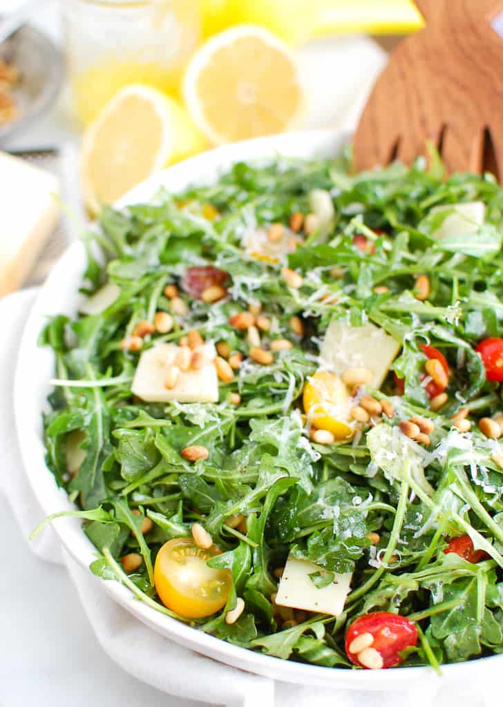 Lemon arugula salad in a bowl with parmesan cheese and pine nuts. 
