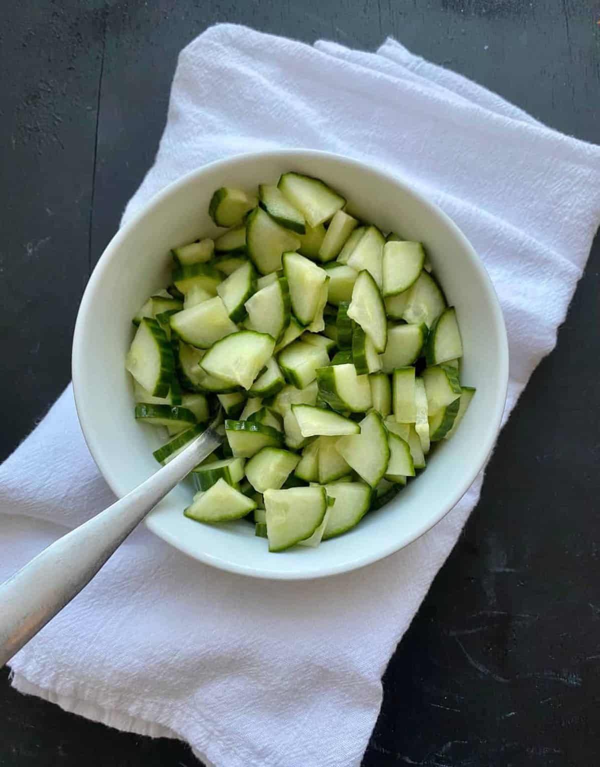 Asian pickled cucumbers in a bowl sitting on a towel. 