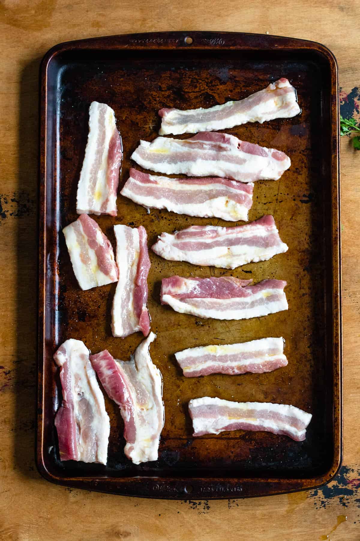 Raw pork belly slices for preparing Stegt Flaesk on a baking sheet. 