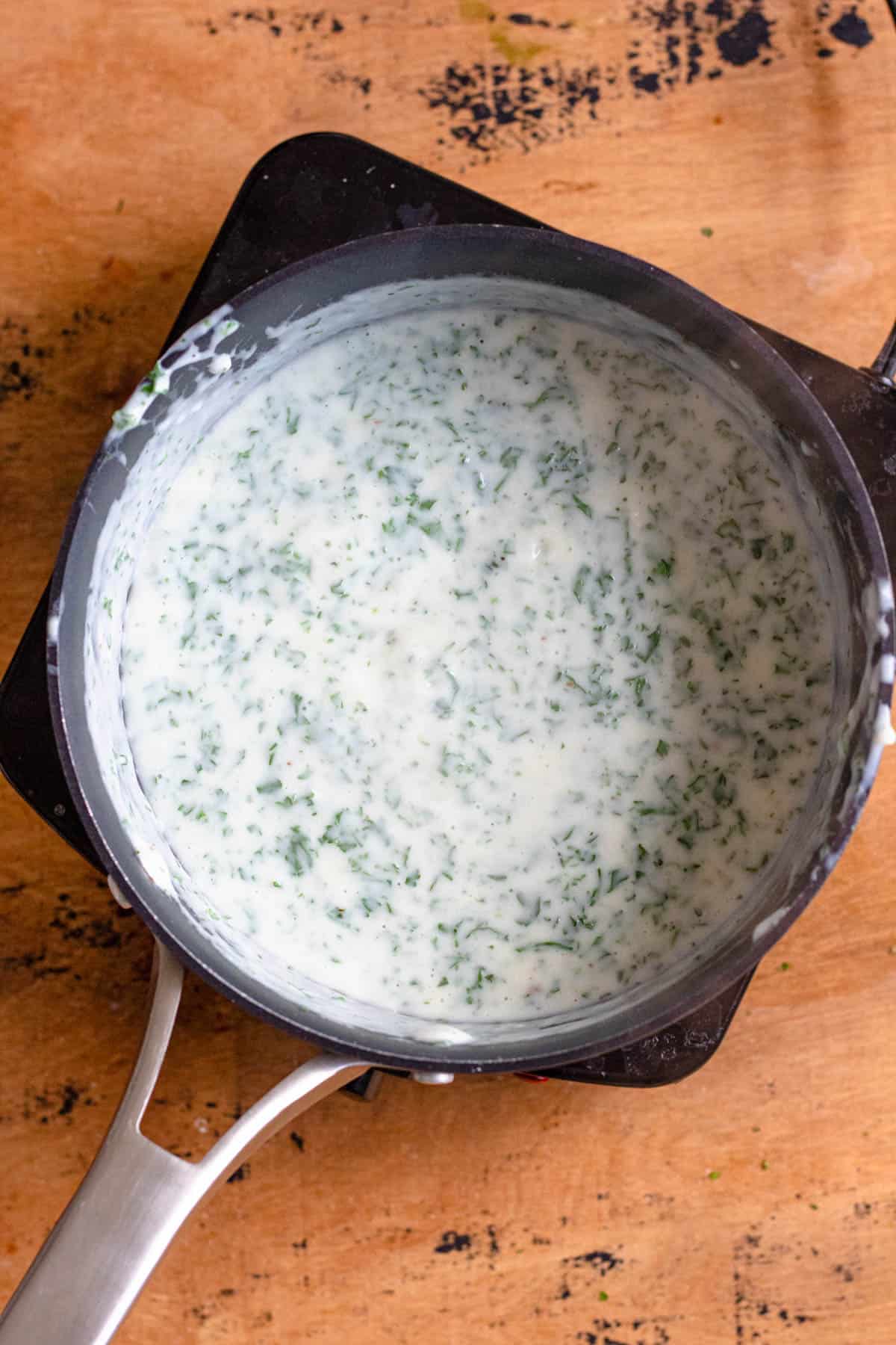 Parsley sauce in a saucepan used to assemble Stegt Flaesk. 