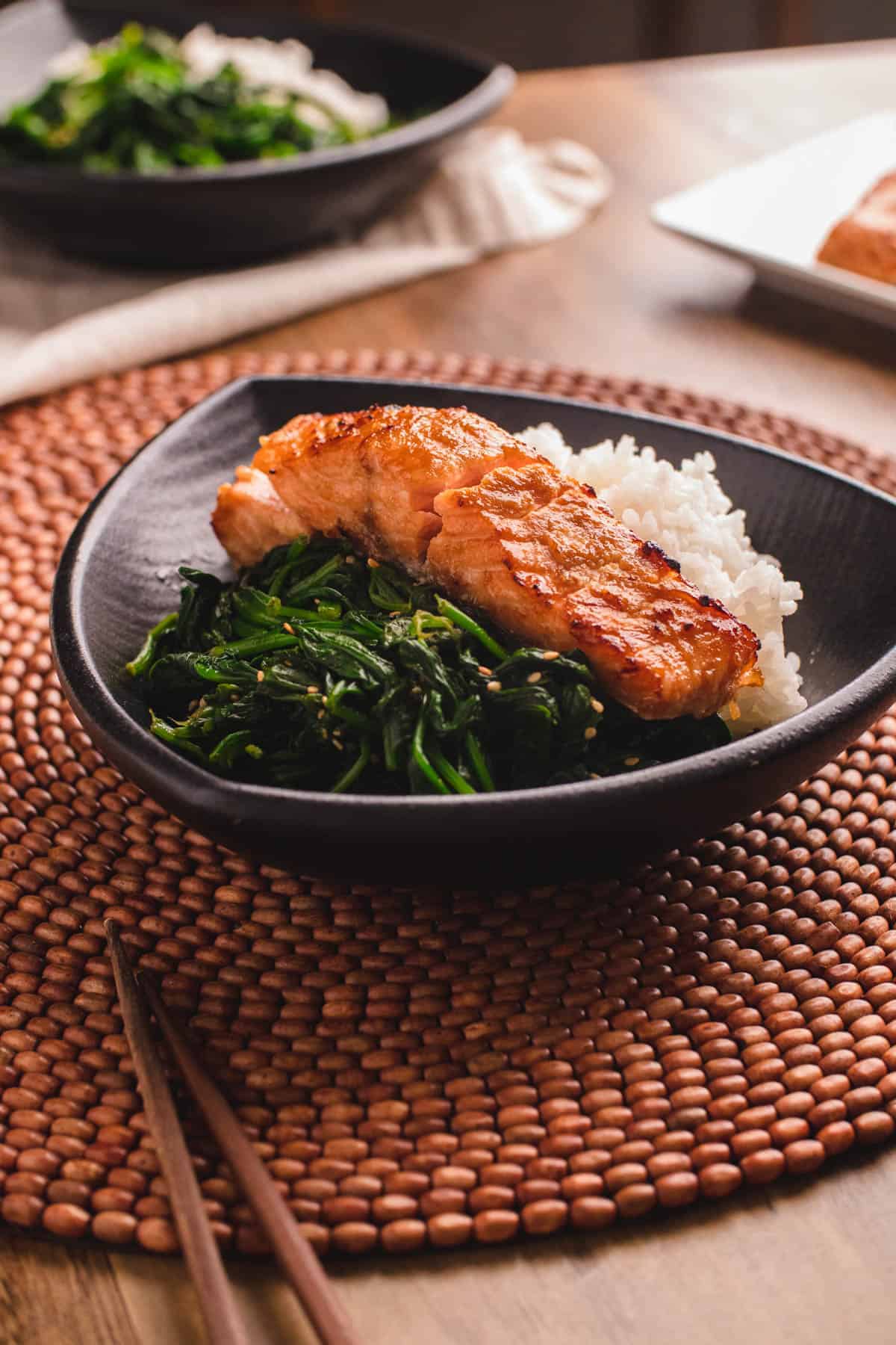 Air fryer miso-glazed salmon served on a plate with a side of white rice and greens. 