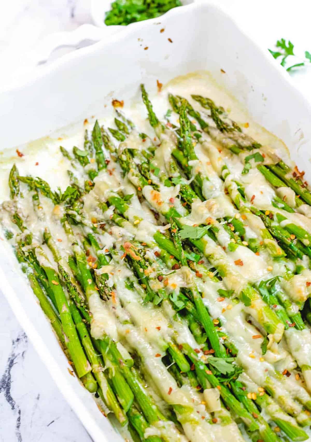 Cheesy baked asparagus in a baking dish. 