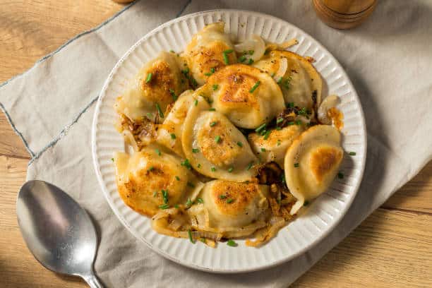 Plate of Pierogi's with a spoon resting next to it. 