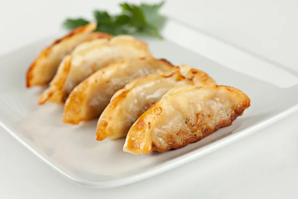 Platter of potstickers with a sprig of parsley. 
