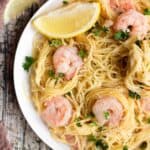 Partial top view of a plate of shrimp scampi prepared in the instant pot, served with a lemon wedge.