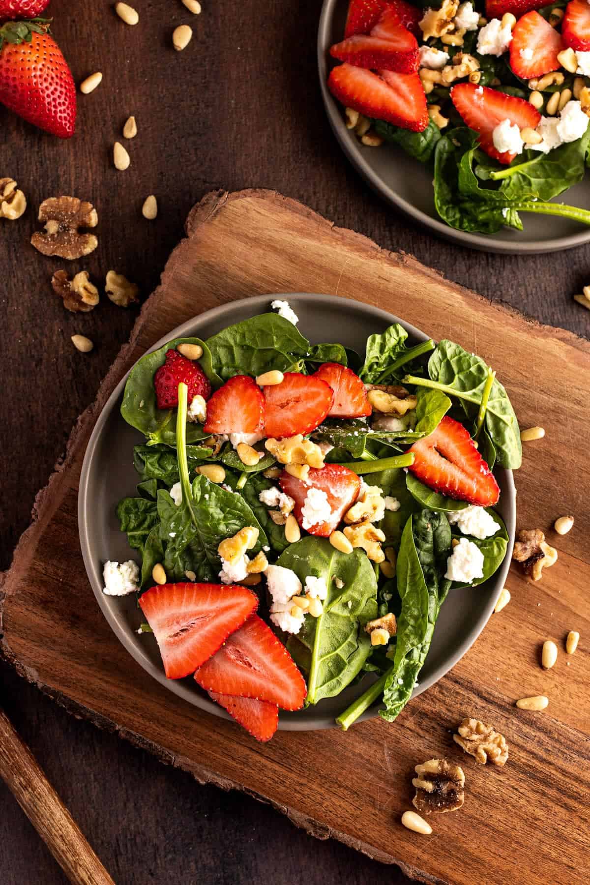 Strawberry goat cheese salad with pine nuts and walnuts garnished on top.