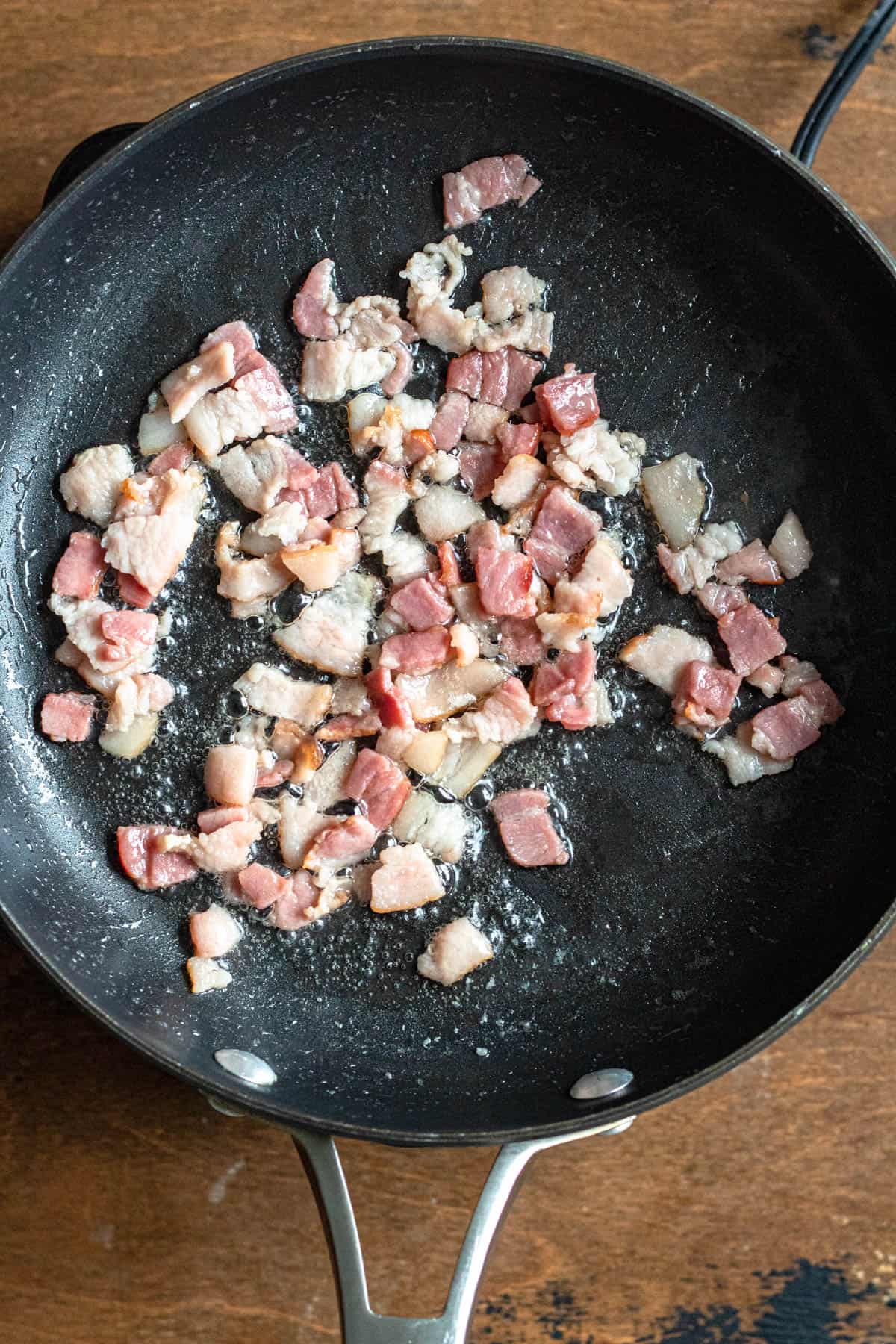 Diced bacon being sauted to a crisp for farofa. 