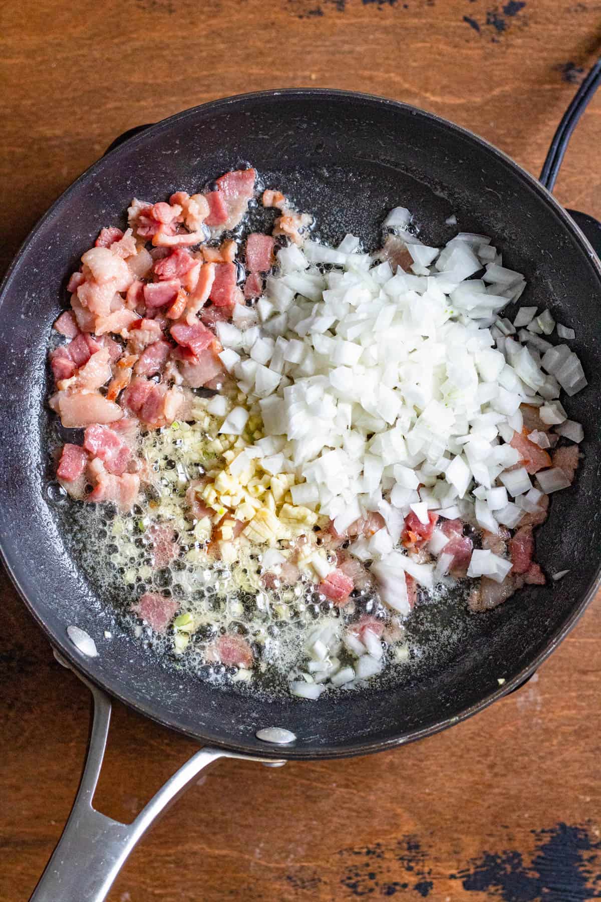 Onions, garlic added to the skillet with bacon for farofa. 