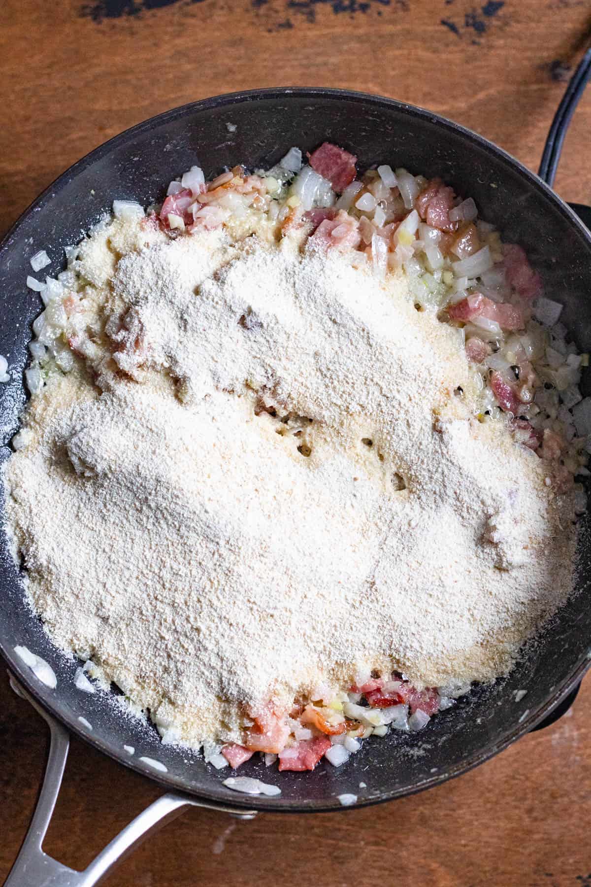 Cassava flour added to the bacon mixture in the skillet. 
