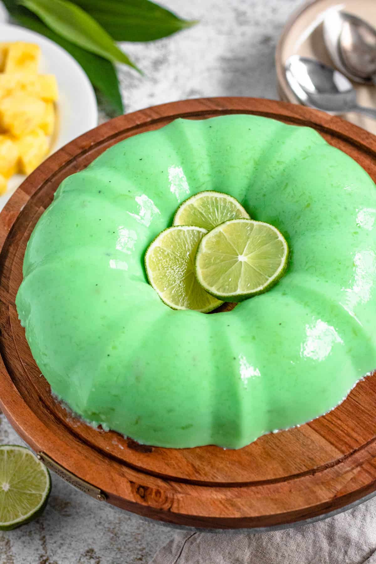 A lime jello salad on a cake stand with lime slices garnished on top. 