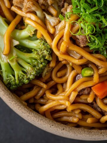 Close up of lo mein with noodles, broccoli, and green onions.