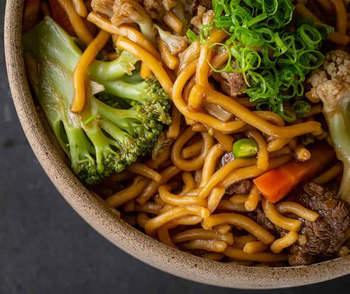 Lo mein in a bowl with stir fried veggies. 