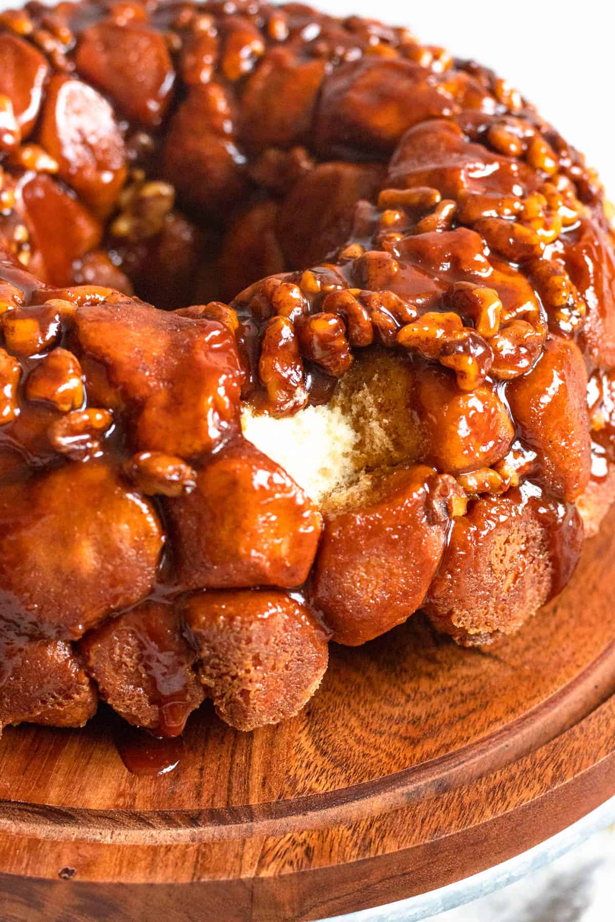 Monkey bread with a piece pulled out showing the baked bread and caramelized pecans inside. 