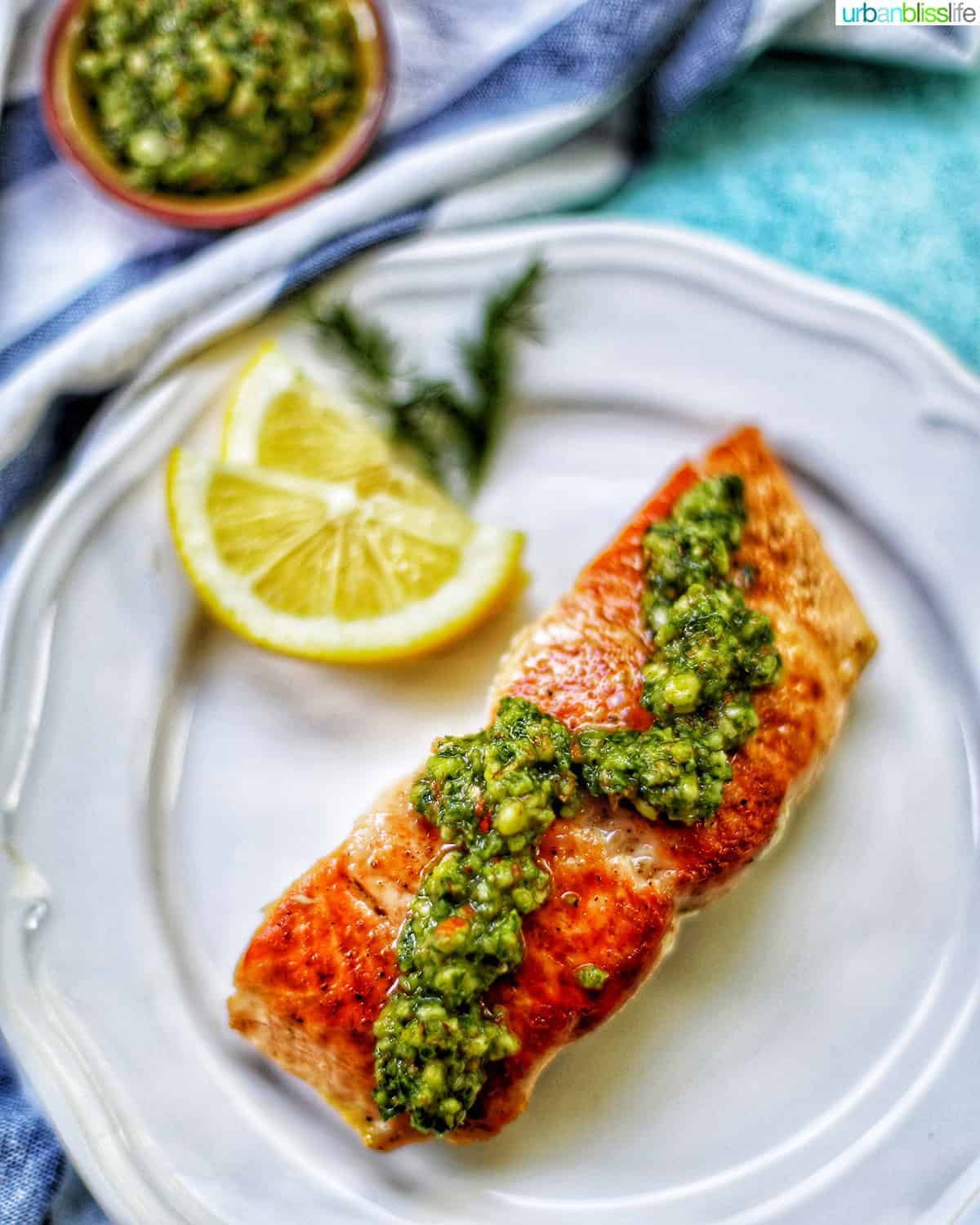 Pan-seared salmon with almond basil pesto over the top and lemon wedges on the side. 