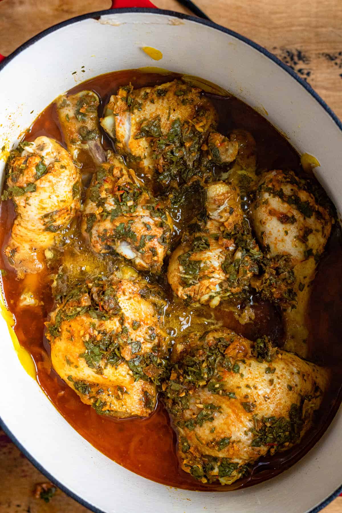 Moroccan Chicken Tagine Recipe simmering in sauce in a Dutch oven. 