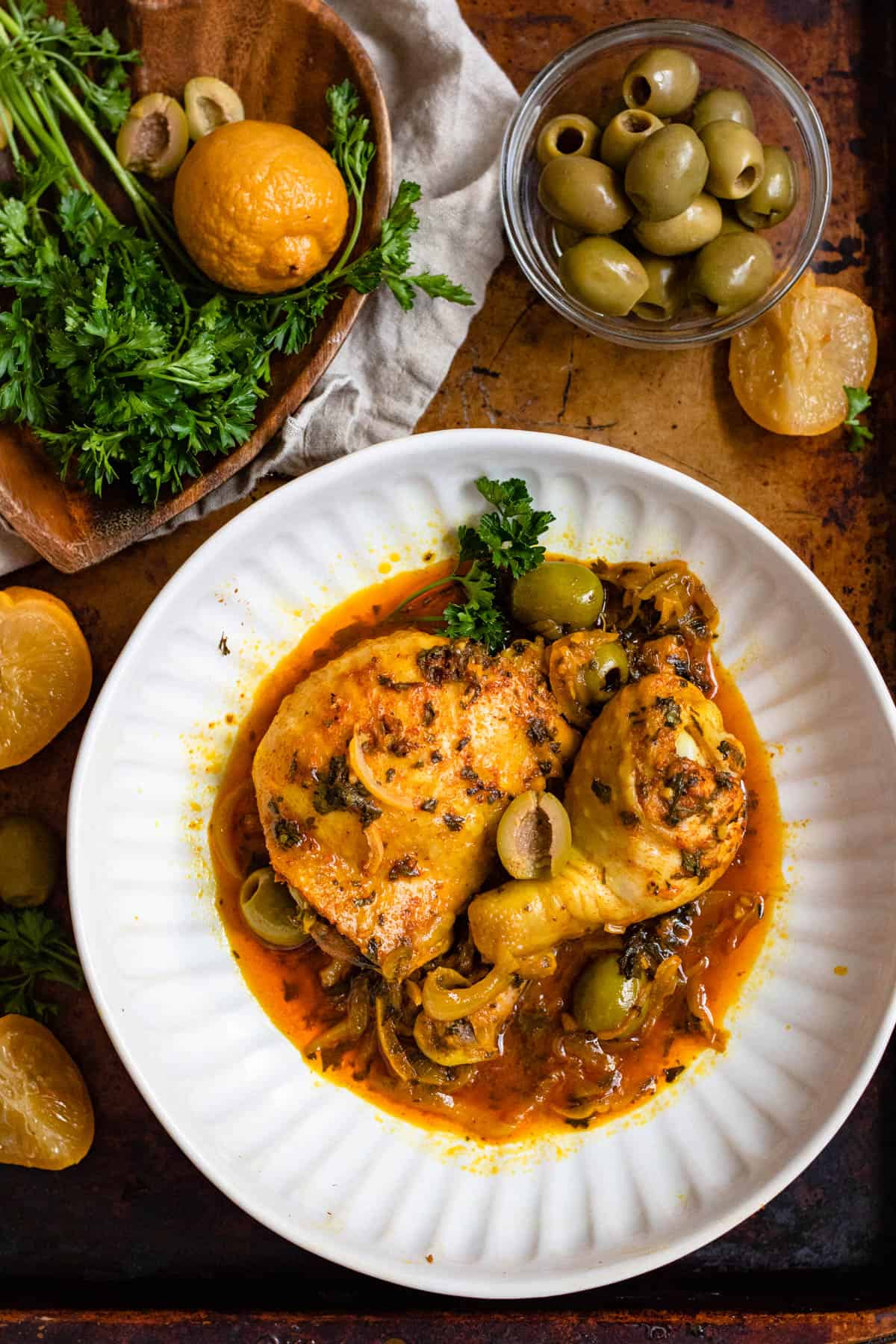 Plate of Moroccan chicken tagine recipe ready to enjoy with a small bowl of pitted green olives served on the side. 
