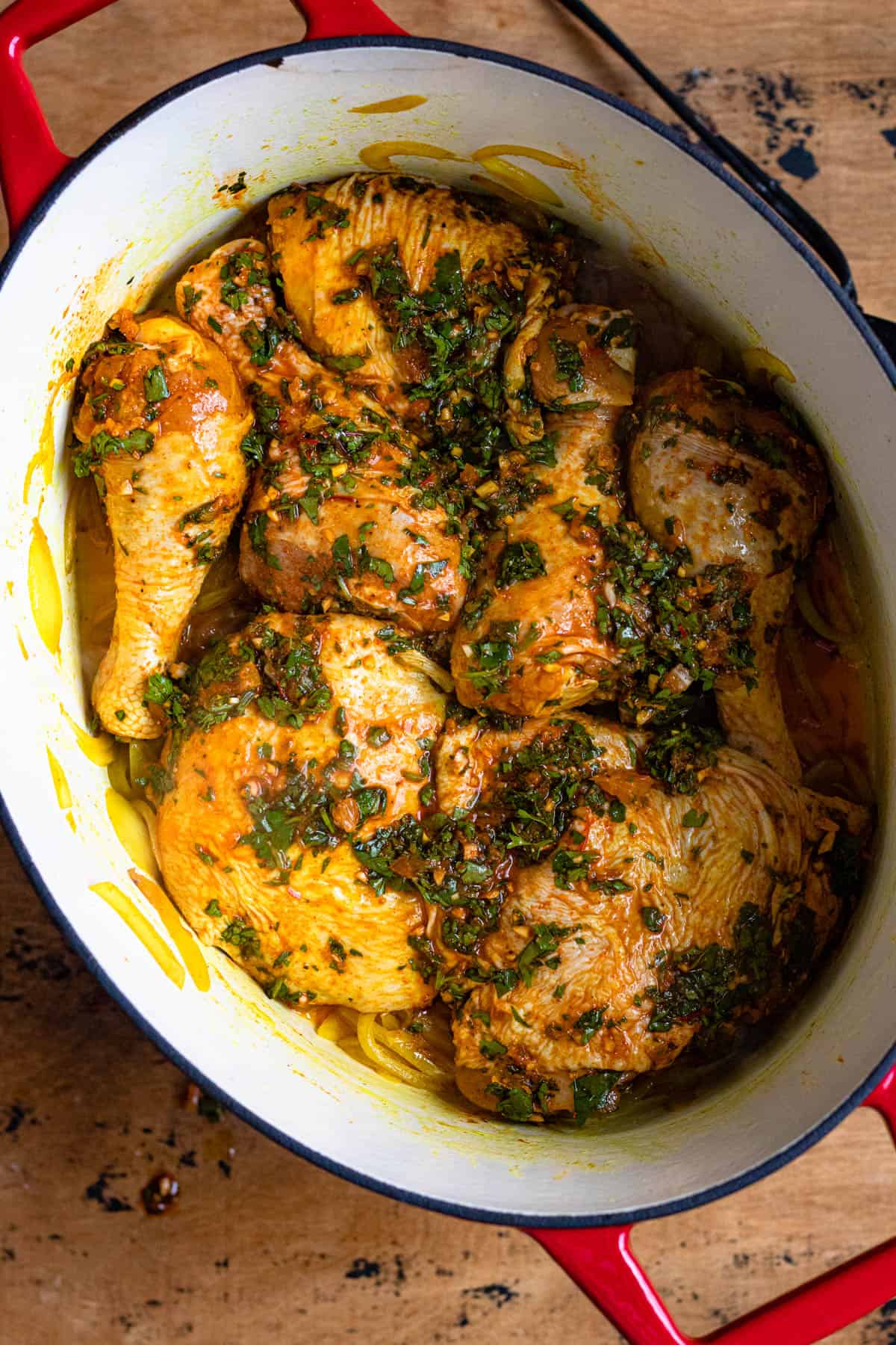 Marinated chicken over sauted onions in a Dutch oven for Moroccan chicken tagine recipe. 