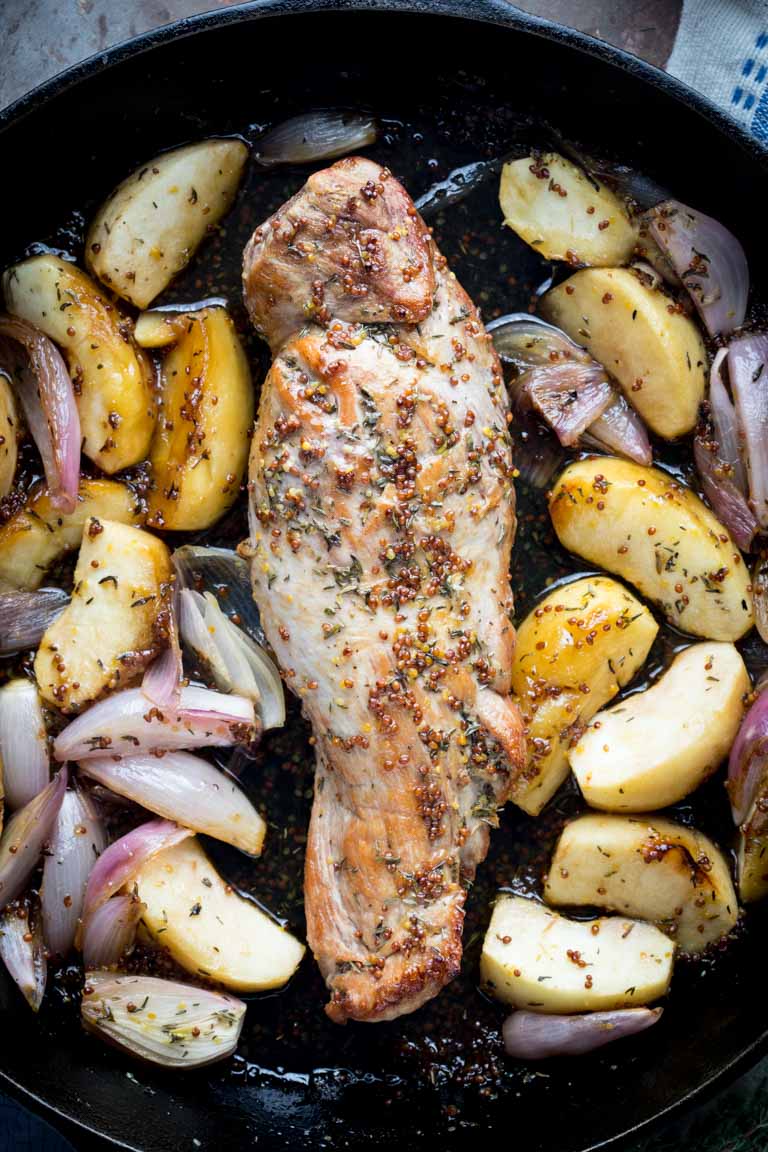 Skillet with roasted pork tenderloin with apple slices and red onions. 
