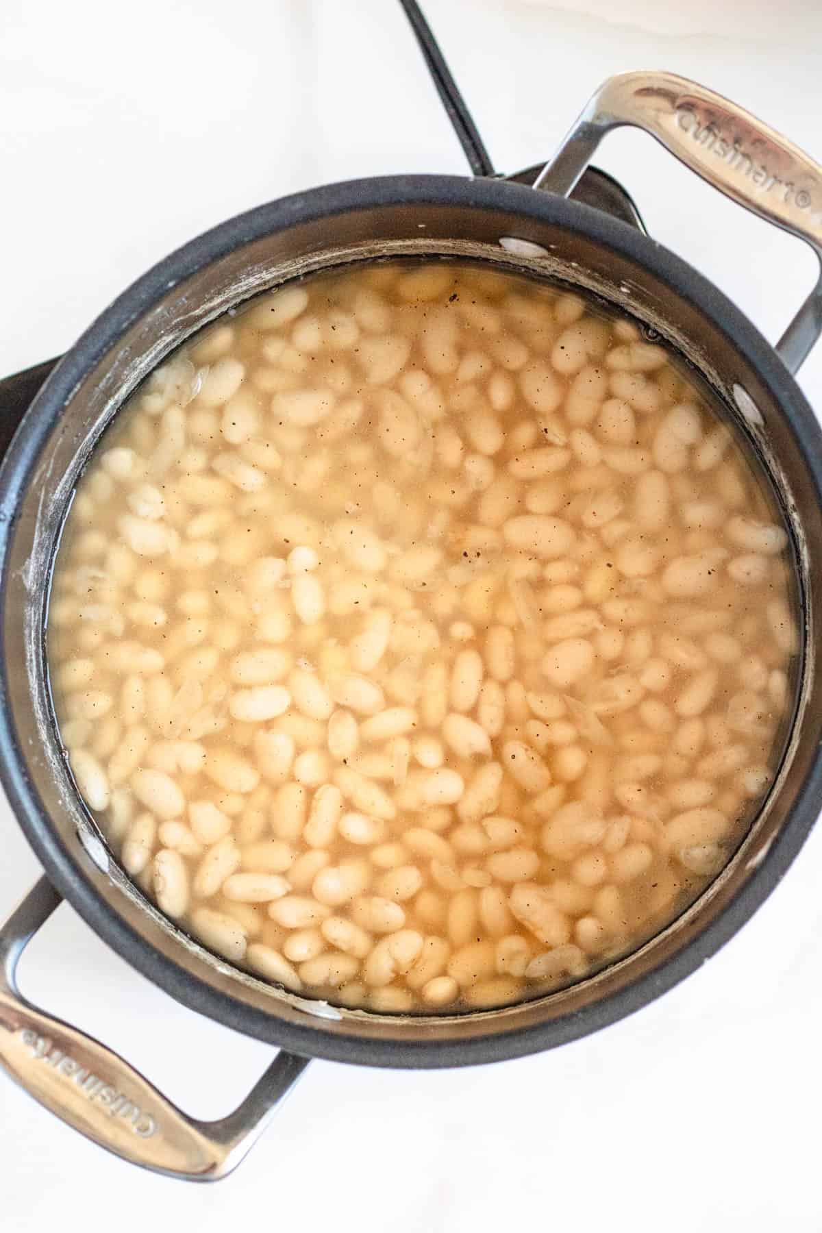 White beans cooking in a saucepan for fagioli or white bean soup.