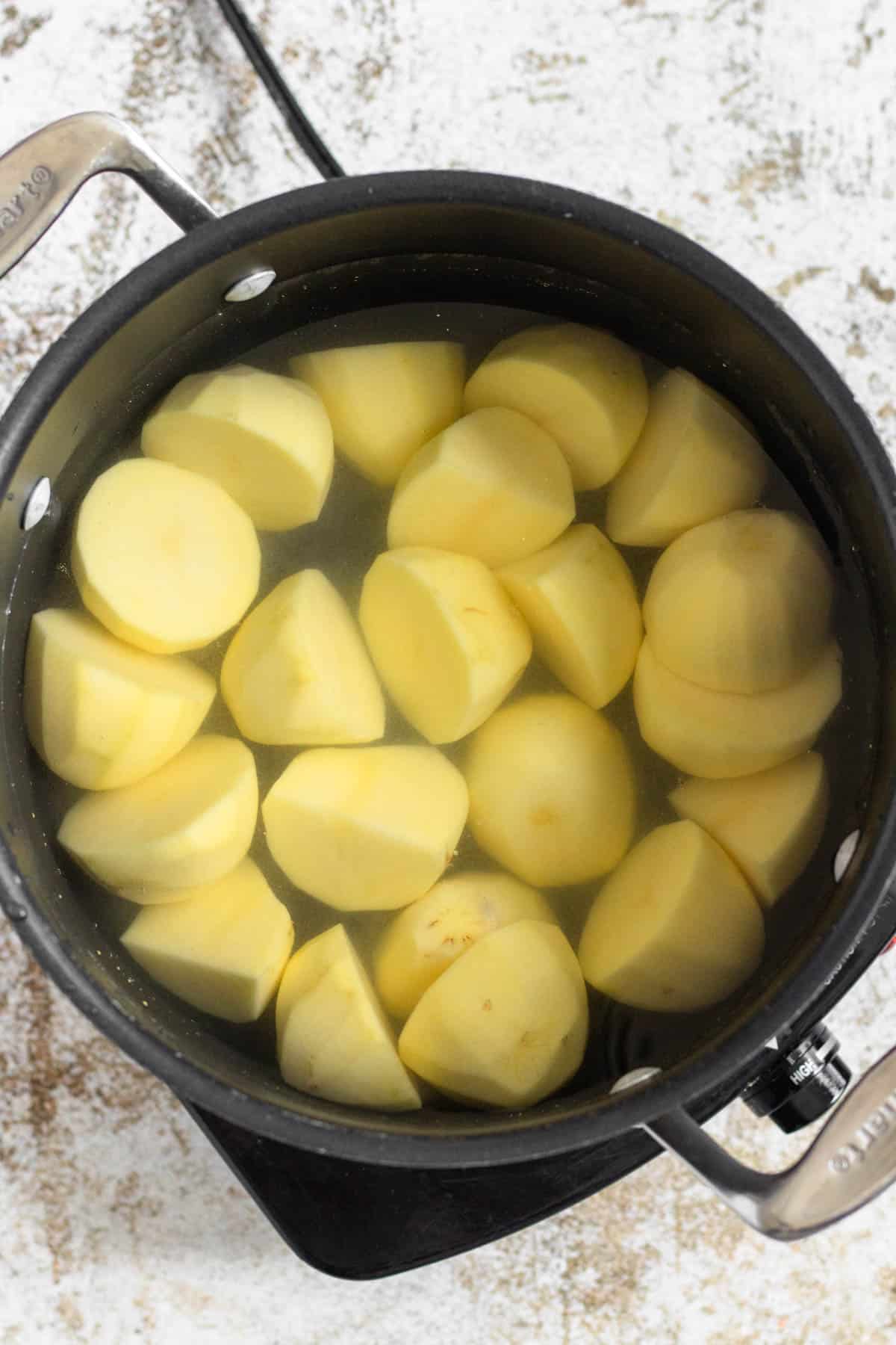 Peeled and halved potatoes in a saucepan, covered with water. 