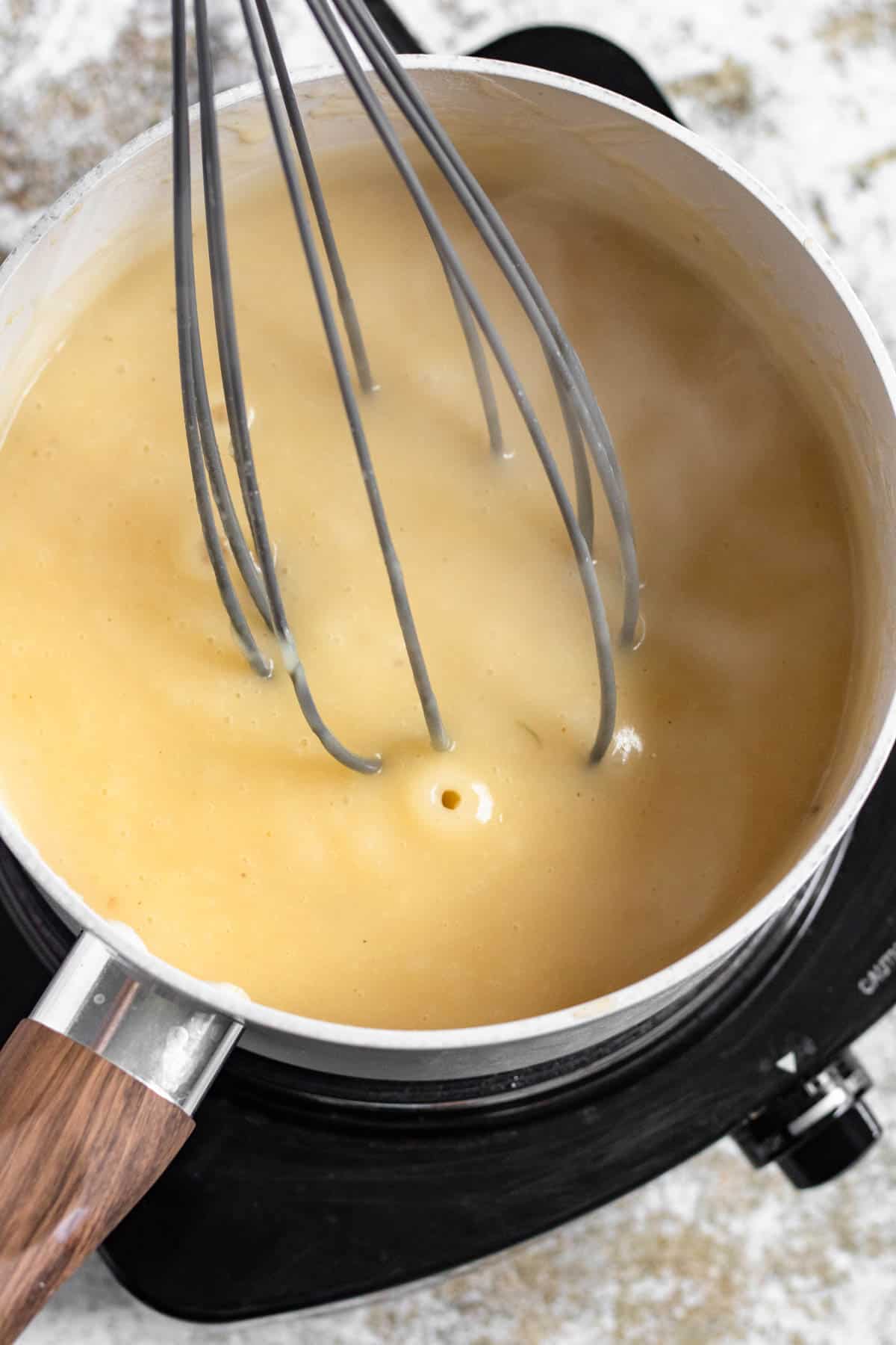 Wire whisk resting in a saucepan with creamy gravy prepared. 