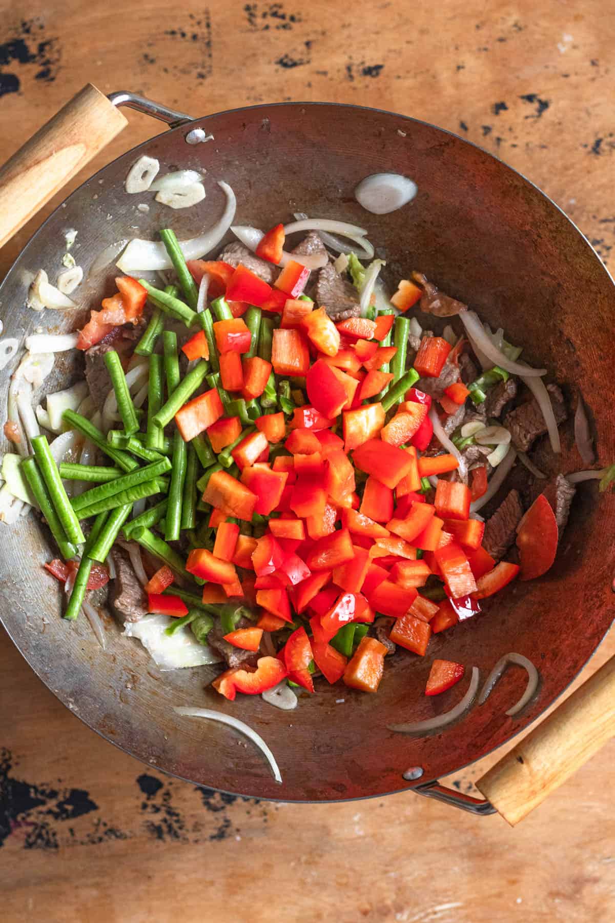 Sliced veggies added to the steak in the wok for making Lagman. 