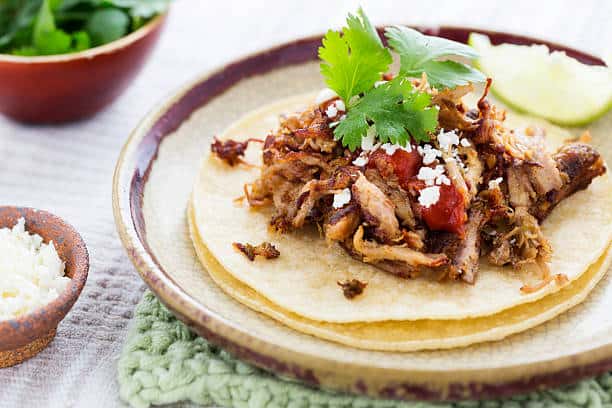 Carnitas served over two corn tortillas and topped with cheese, salsa and cilantro with a lime wedge on the side. 