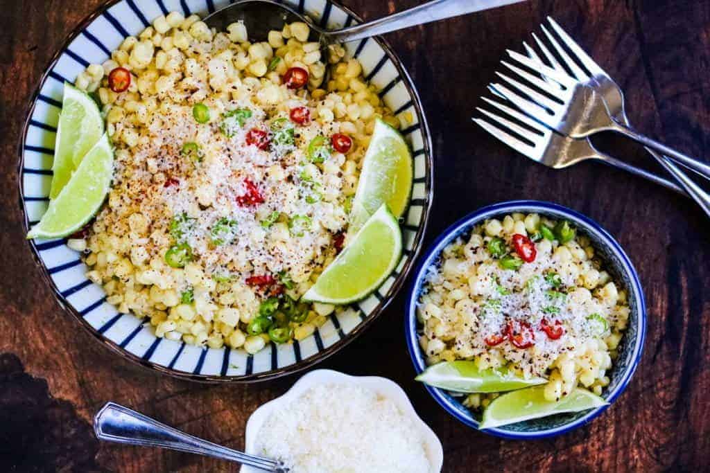 Two bowls of Mexican corn salad with chiles, lime and Parmesan. 