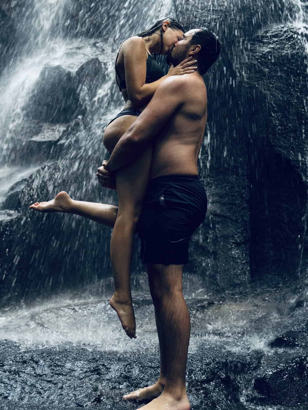 A man and woman kissing in a waterfall. 
