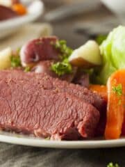 Corned Beef on a plate with cooked carrots and cabbage.
