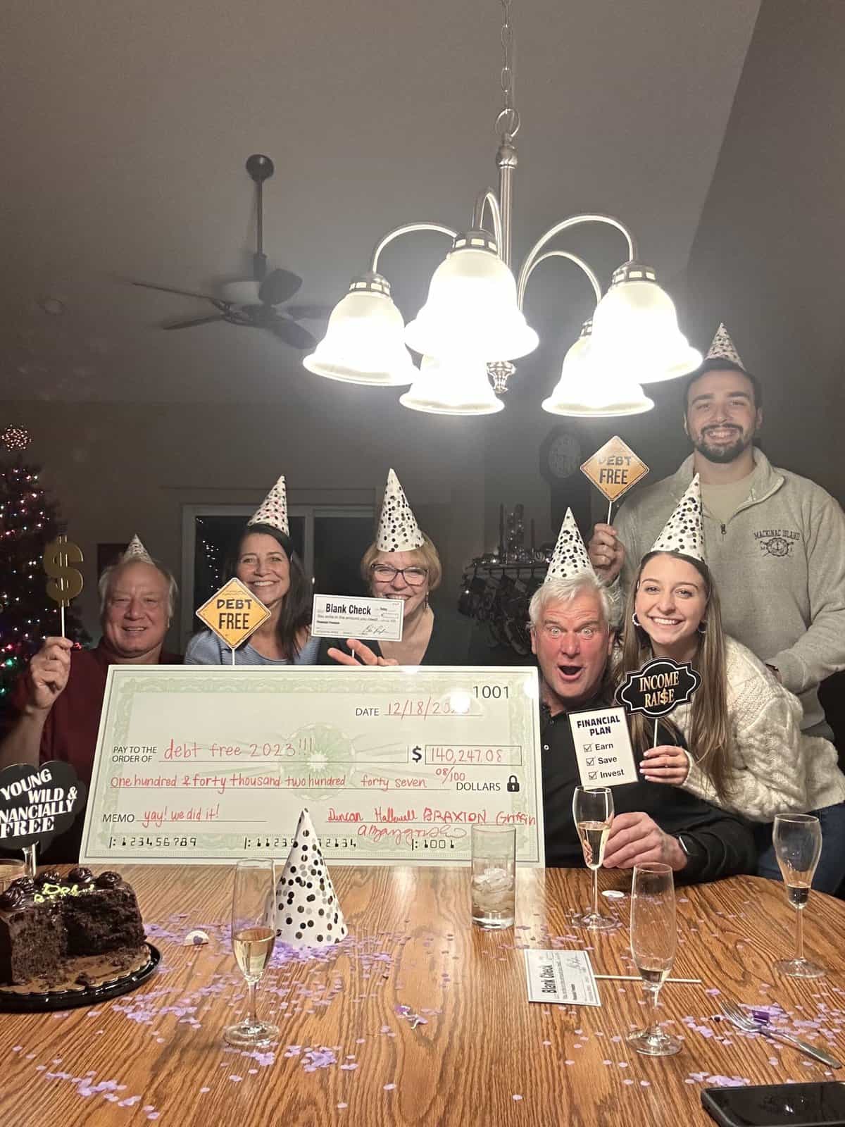 A family posing for a Debt Free party with a giant check. 
