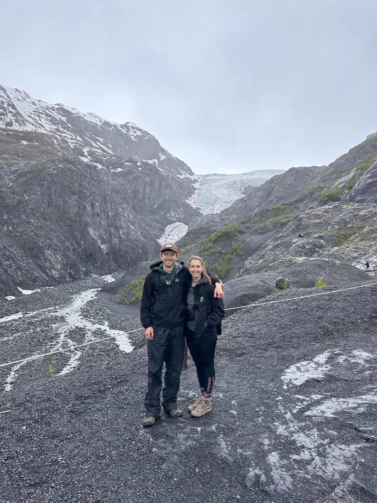 A man and woman posing in front of Exit Glacier in Alaska. 