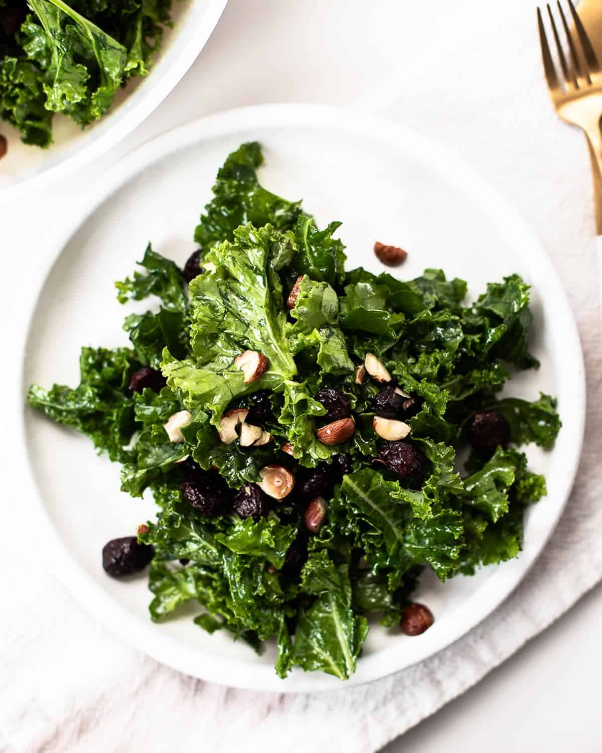 Plate with a kale salad with cranberries, hazelnuts and turmeric vinaigrette. 