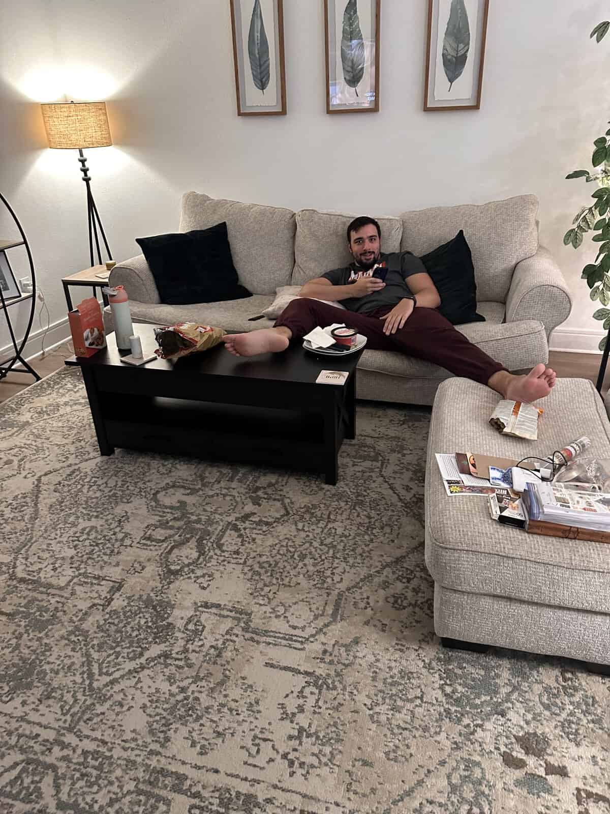 A man laying in a weird position on the couch. 