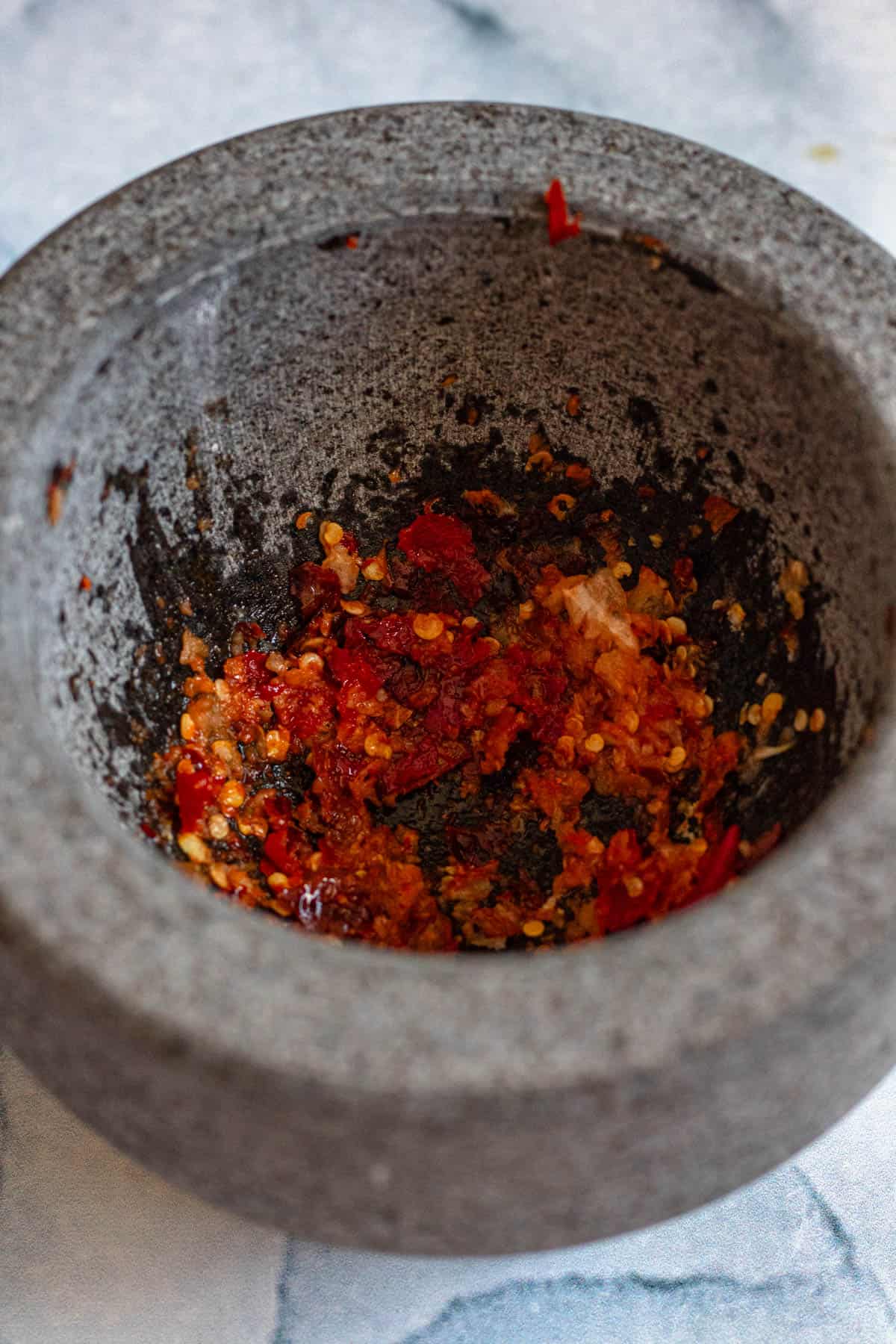 Mortar filled with fresh and dried chili peppers that are mashed together with salt and garlic. 